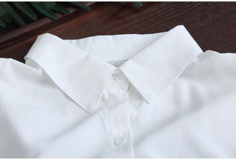 Camicia da donna bianca a tinta unita, media lunghezza, per esportazione transfrontaliera, estiva, casual, ampia, davanti corta, dietro lunga, ideale per il sole._voghion.com