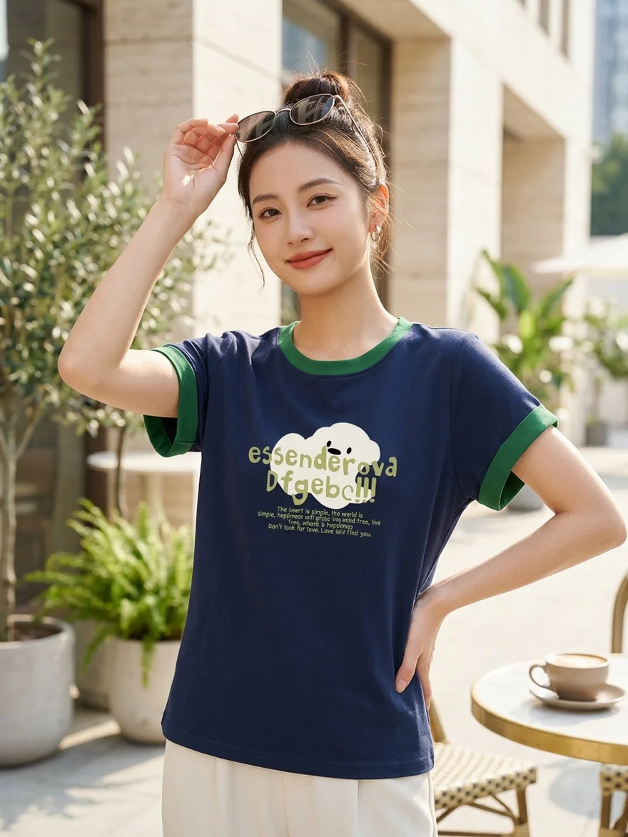 女性穿深蓝色绿边印花上衣,手扶头顶太阳镜,背景为明亮户外环境